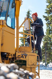 Woman climbs snow grooming machine wearing Britt Utility HOTSWAP™ Pant in Black Thermal Denim