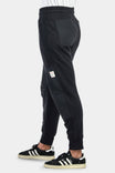 Side view of a woman wearing Dovetail Workwear's Flagger Fleece Jogger Work Pant in Black, showing reinforced knees and tapered leg design with elastic cuff.