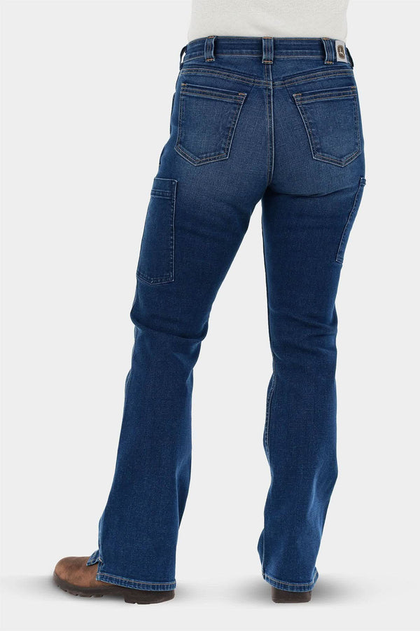 Back view of a woman wearing John Deere X Dovetail Workwear Into Town Bootcut Jeans in Classic Indigo Blue, showing reinforced back pockets and bootcut leg over work boots