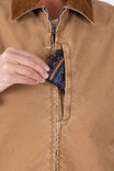 Detail of Dovetail Workwear's Old School Trucker Vest in Vintage Brown, showing the zip chest pocket and light quilted insulation visible inside as a woman reaches toward it