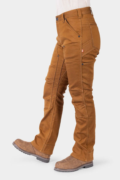Side view of a woman wearing Dovetail Workwear's Britt Utility HOTSWAP™ Pant in Saddle Brown Thermal Denim, showcasing the straight leg fit, cargo-style pockets, and tool loop details