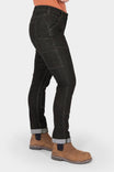 Side view of a woman wearing Dovetail Workwear's Maven Slim Pant in Heathered Black Graphene, cuffed at the ankles, paired with tan work boots