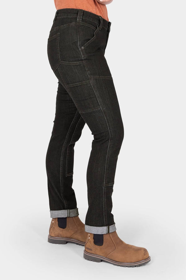 Side view of a woman wearing Dovetail Workwear's Maven Slim Pant in Heathered Black Graphene, cuffed at the ankles, paired with tan work boots