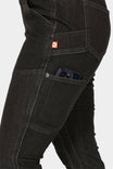 Side view of a woman wearing Dovetail Workwear's Maven Slim Pant in Heathered Black Graphene, showcasing the phone pocket and reinforced thigh panel with visible tool loop
