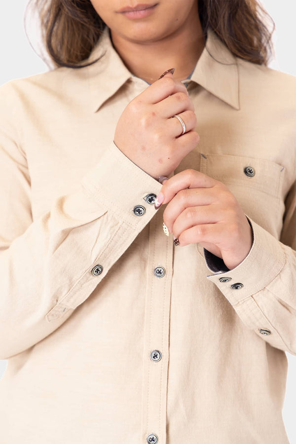 Detail view of a woman buttoning the Givens Long Sleeve Summer Work Shirt in Ecru White by Dovetail Workwear, showing the button chest pocket and contrast cuff details