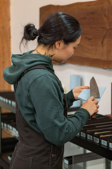 Side view of a woman wearing the Dovetail Workwear GO TO™ Hoodie in Lodge Green, displaying the reinforced elbow and hidden phone pocket details