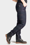Side view of a woman wearing Dovetail Workwear's Britt Utility Pant in FR Denim Indigo, showing cargo pockets, reinforced knees, and straight leg silhouette with work boots