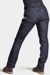 Back view of a woman wearing Dovetail Workwear's Britt Utility Pant in Indigo FR Denim, showing reinforced knees, cargo pockets, and straight leg fit with cuffed hem