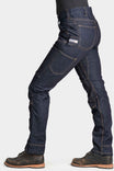 Side view of a woman wearing Dovetail Workwear's Britt Utility Pant in FR Denim, showing the straight leg fit, reinforced knees, and cargo-style pockets in Indigo.