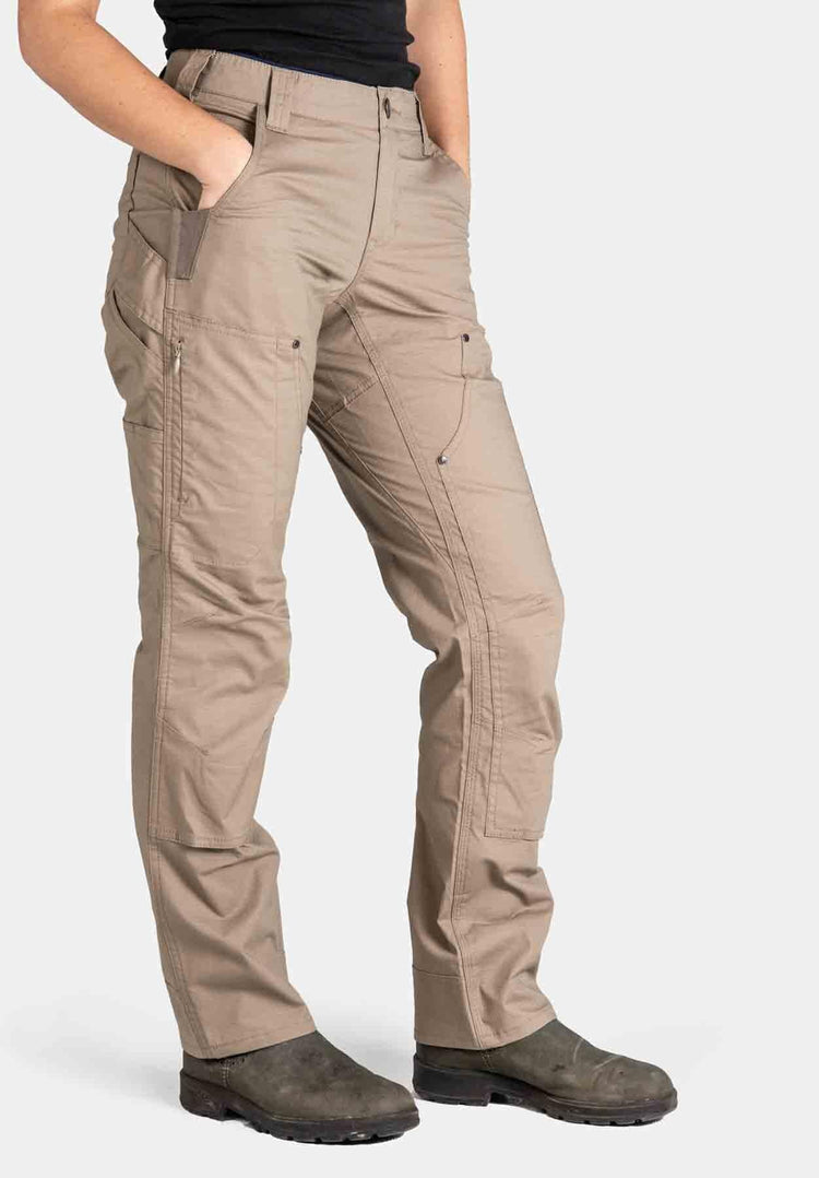 Side view of a woman wearing the Dovetail Workwear Britt X Ultralight Work Pant in Flax Ripstop, showcasing cargo-style pockets, reinforced knees, and straight leg silhouette
