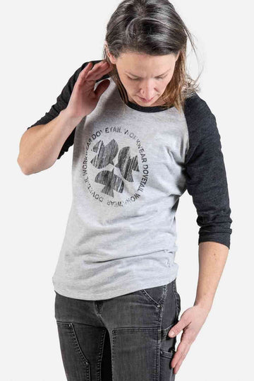 Woman wearing the Dovetail Workwear 3/4 Logo Work Shirt in charcoal with charcoal raglan sleeves, featuring the triple dove icon logo and rounded hemline